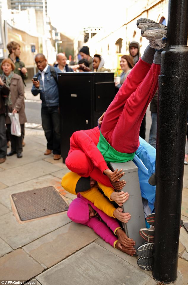  p>几个身穿五颜六色衣服的人,挤在一起摆出各种高难度动作,旁观者被