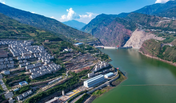 左边是水库建设移民搬迁安置点，远处是白鹤滩水电站大坝