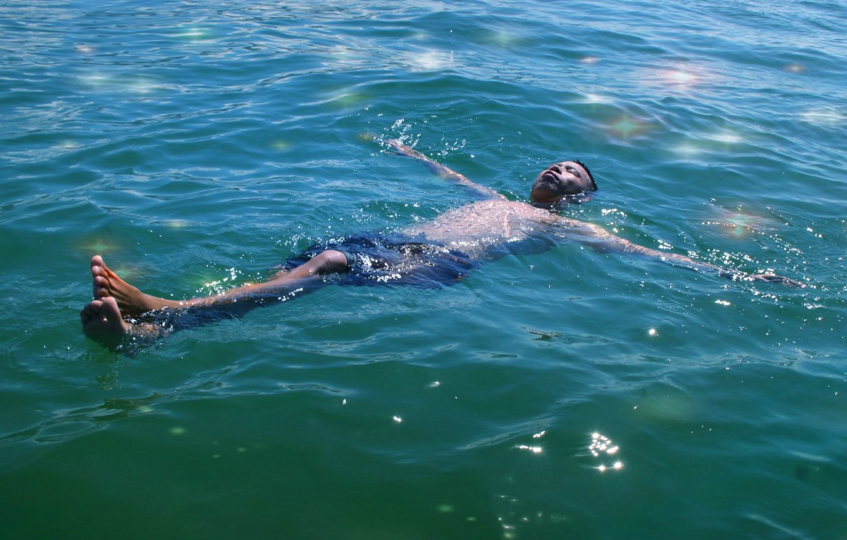 的姿态躺在水面上,面部露出水面,手脚静止不动,长时间漂浮的一个过程