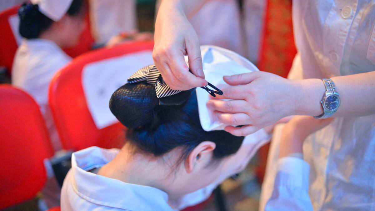 护生直跪在护理前辈面前,前辈为护生戴上圣洁的燕尾帽,护生接过前辈手